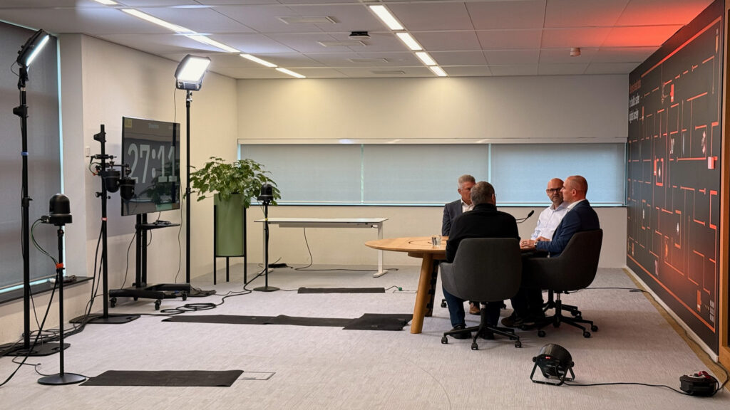 On-location setup with lighting, compact cameras on stands and a round table with guests