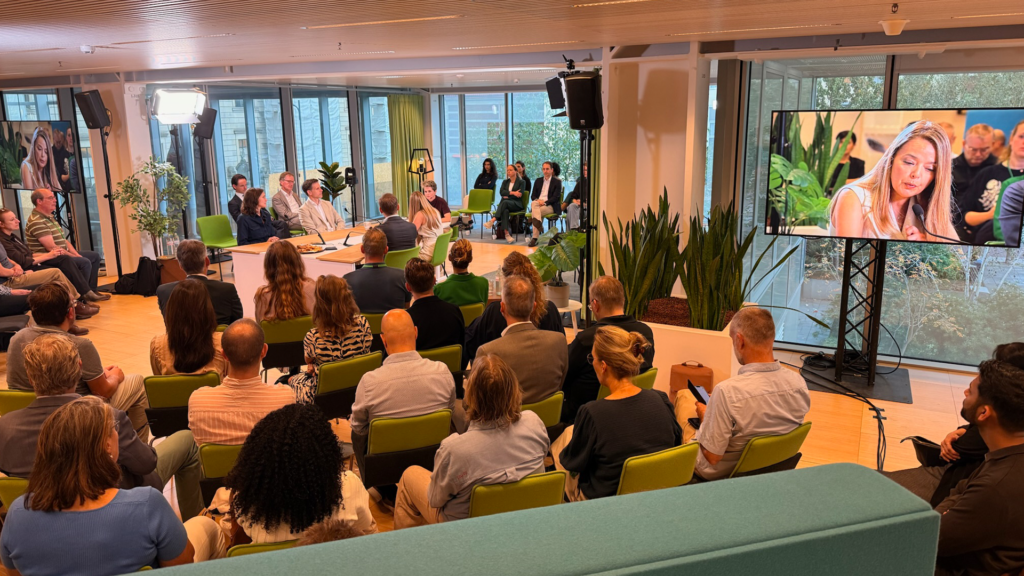 Table discussion with an audience, cameras and large screens during Politiek Café at the Timmerhuis